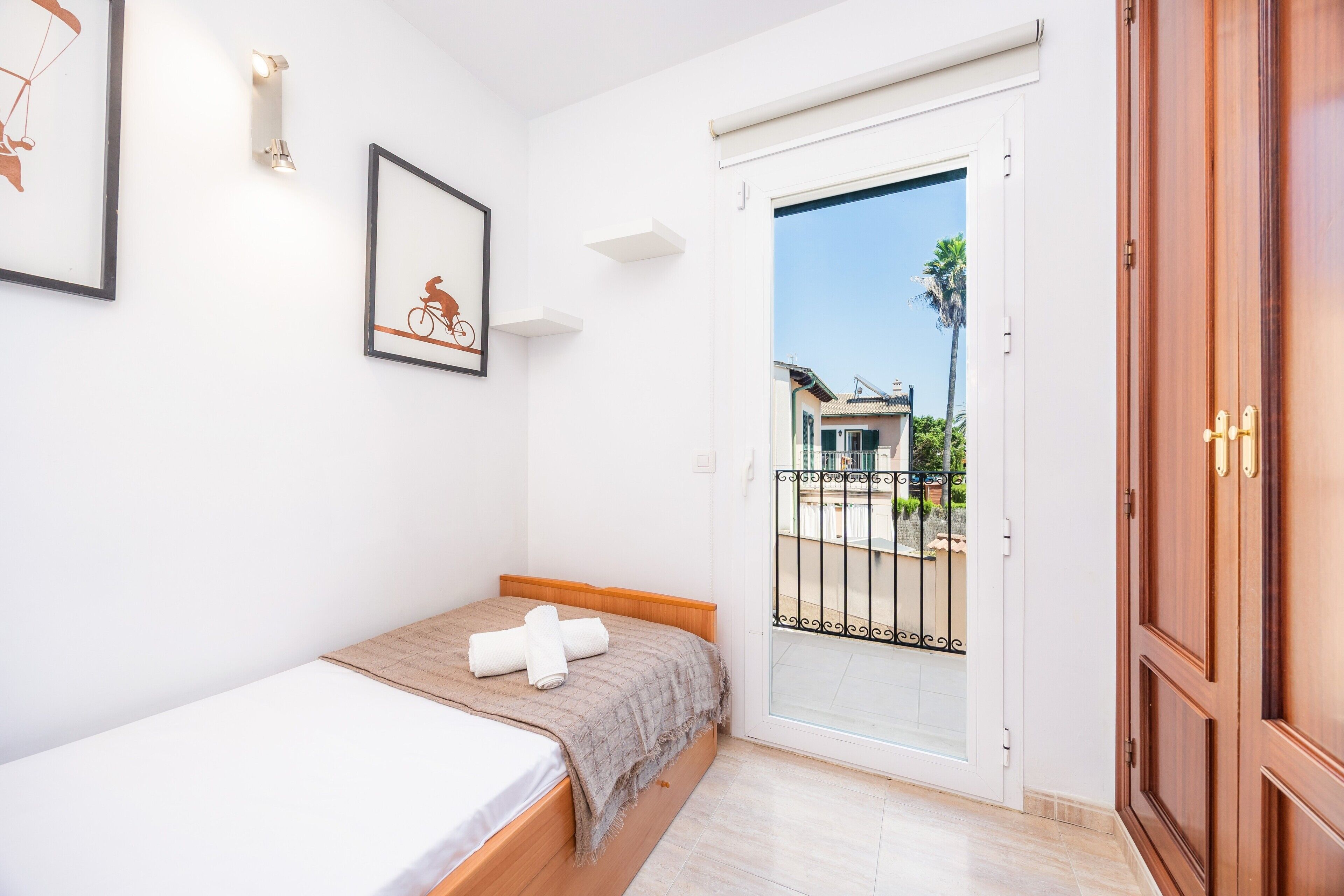 A bedroom with a bed, a door to a balcony, and a wall-mounted light fixture.