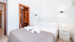 Habitación de hotel con cama, mesita de noche, armario de madera y lámpara de pared.