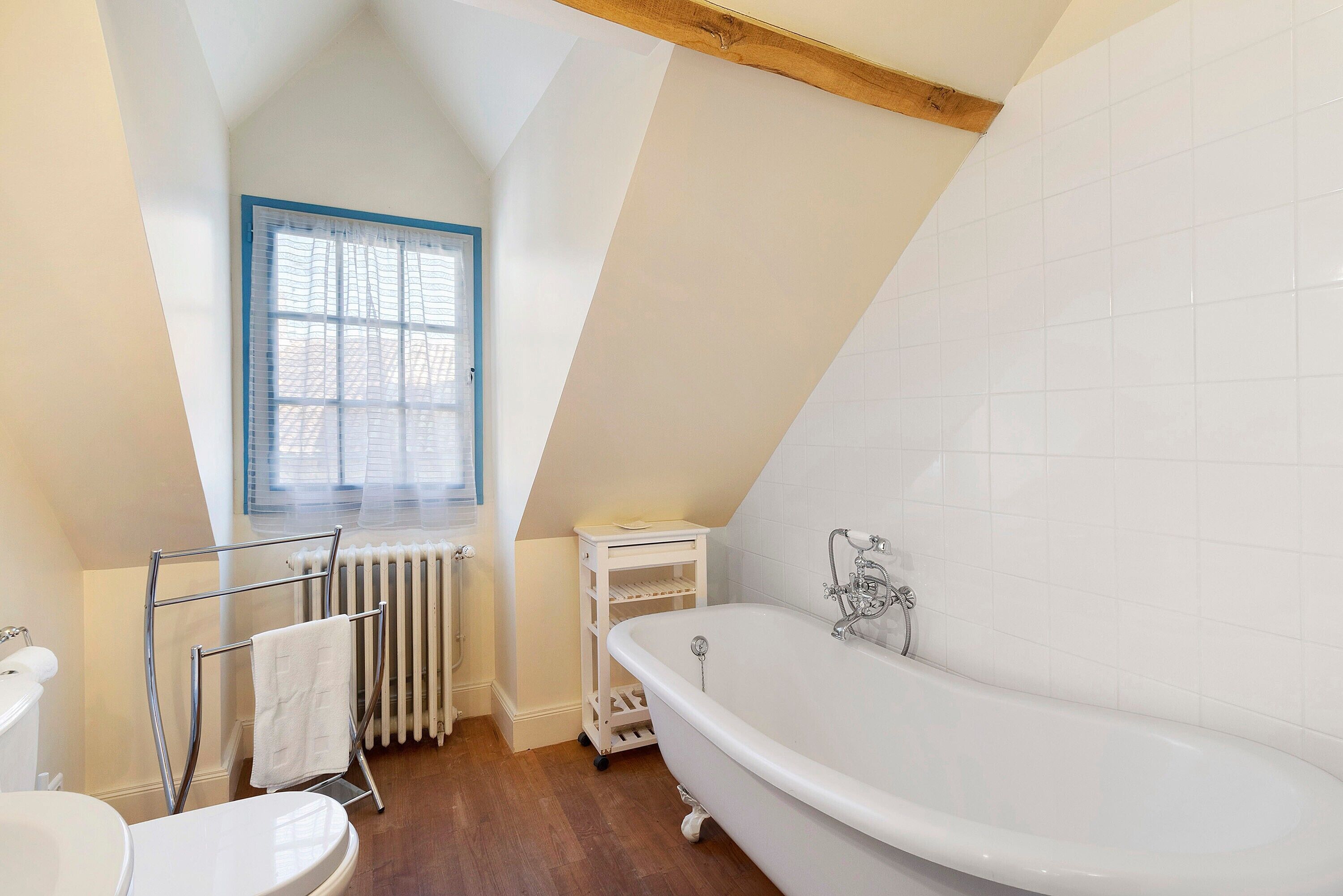 A bathroom with a white bathtub, a window with blue trim, and a radiator.