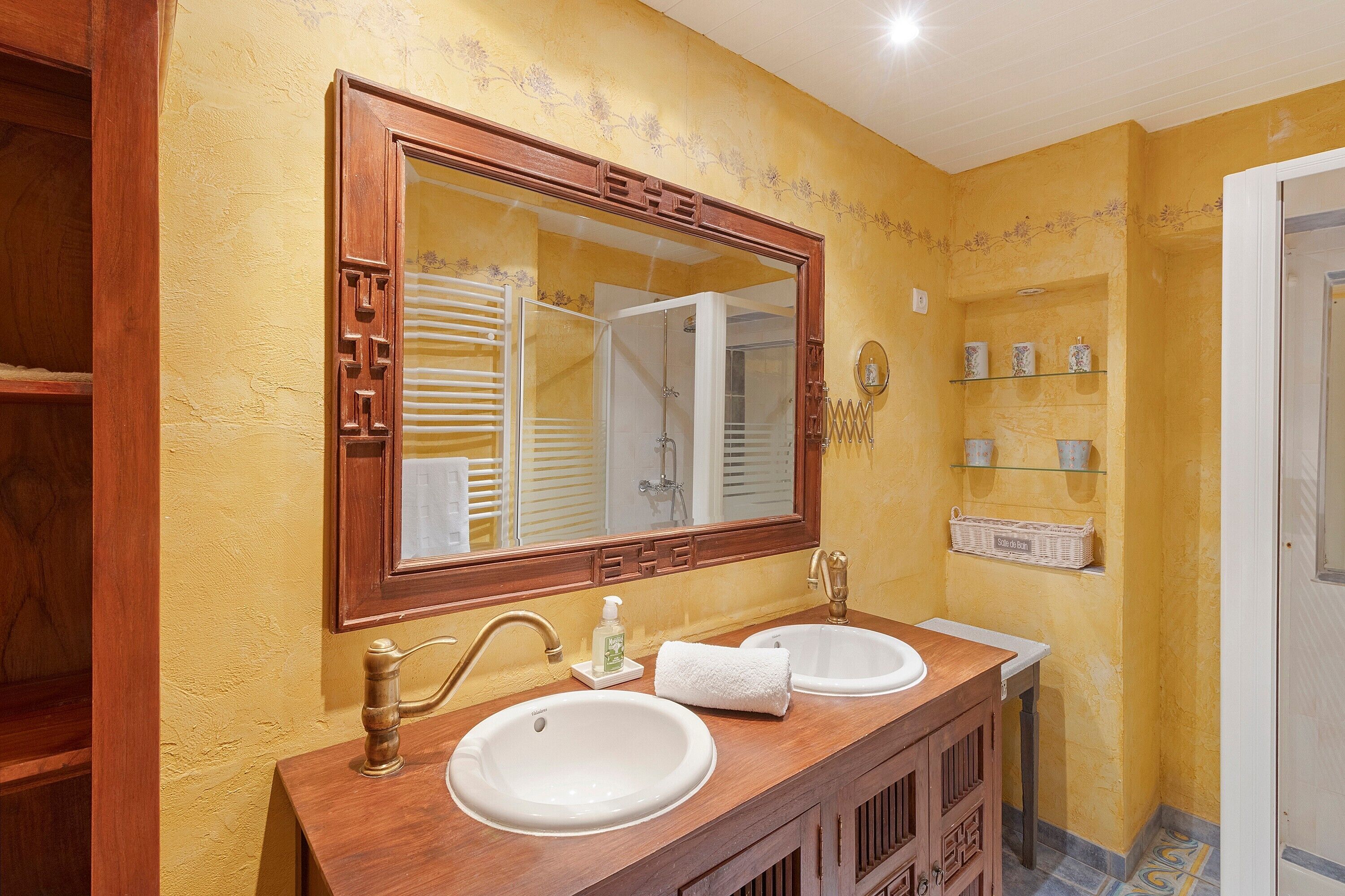 A bathroom with two sinks, a large mirror, and wooden cabinetry.