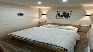A bedroom with a wooden bed, white bedding, and two wall-mounted nightstands. - Family Apartment in La Bourboule (La Bourboule)