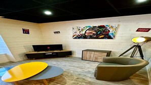A modern living room with a wooden floor, a yellow and grey round table, a brown armchair, a black entertainment unit, and a large abstract painting on the wall. - Family Apartment in La Bourboule (La Bourboule)