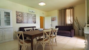 A dining area with a table and chairs, a sofa, a cabinet, and artwork on the walls.