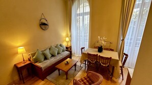 Un salon chaleureux avec un canapé, une table à manger et des chaises, une table basse et un fauteuil en osier.