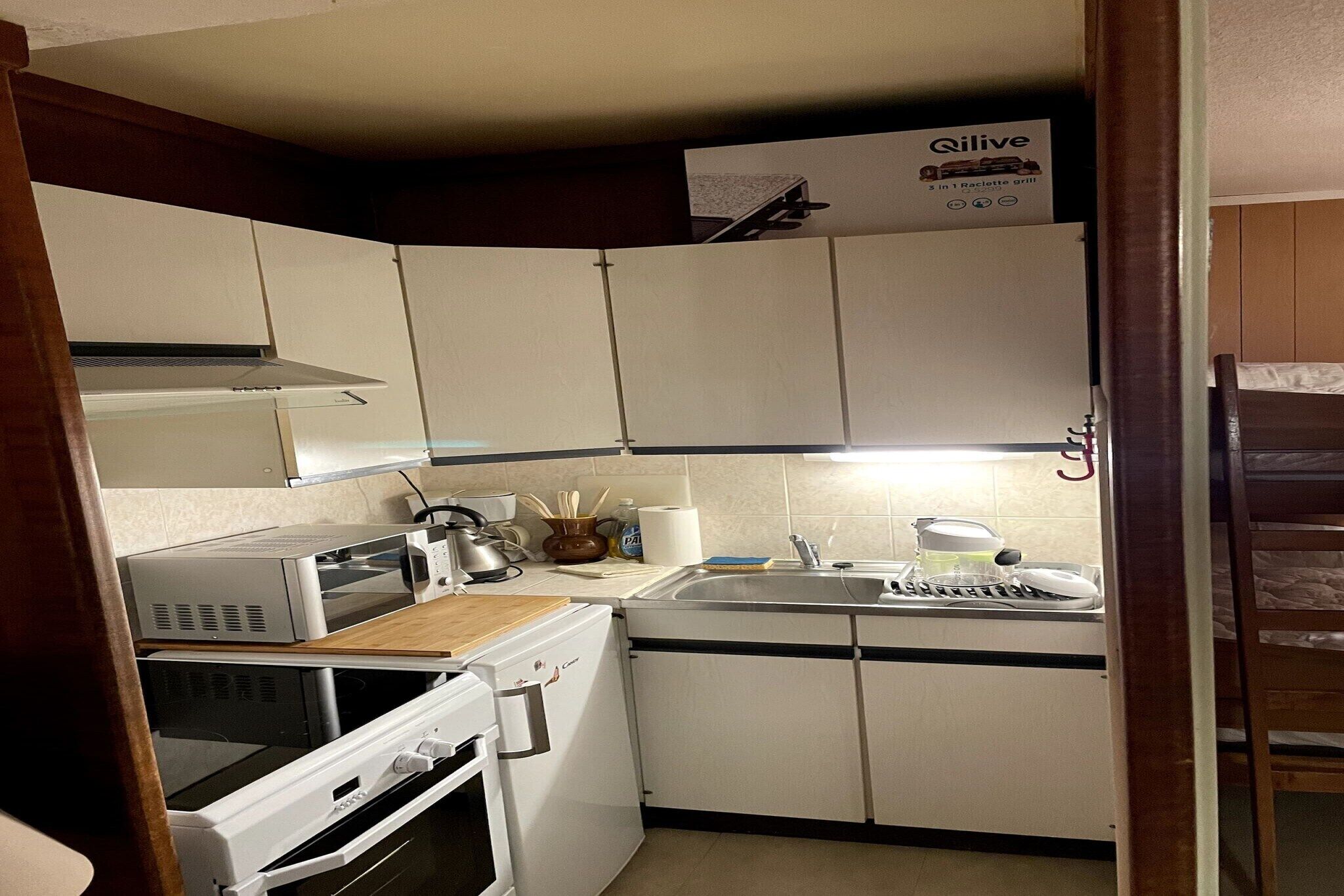 A compact kitchen with white cabinets, a microwave, a toaster, and a sink.