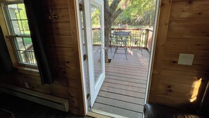 Una cabaña de madera con un cerramiento de vidrio corredizo que da a una terraza exterior con mesa y sillas.