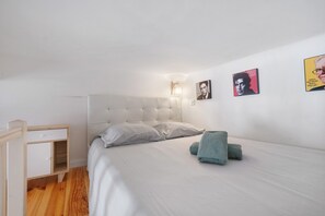 Ein Schlafzimmer mit einem Bett, einem Nachttisch, einer Lampe und Wandbildern.