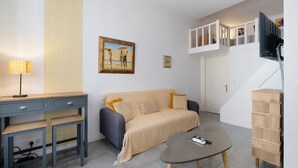 A modern living room with a sofa, a coffee table, a desk with a lamp, and a painting on the wall. - Studio Apartment 'Vintage' with Wi-Fi and Air Conditioning (Nice)