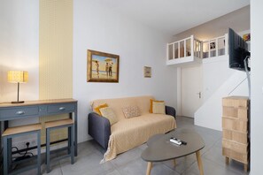Ein modernes Wohnzimmer mit einer Couch, einem Couchtisch, einem Schreibtisch mit Lampe und einem Gemälde an der Wand.