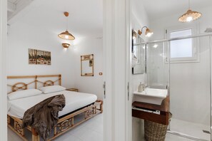 Un dormitorio con cama, lámparas de noche, un cuadro y un espejo en la pared.