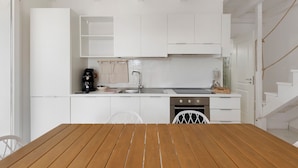 A modern kitchen with white cabinetry, a wooden dining table, and a built-in oven. - Apartment 'Tenuta Degli Asinelli - Casale' with Sea View, Wi-Fi and Air Conditioning (Alliste)