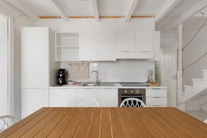 Una cocina moderna con armarios blancos, una mesa de comedor de madera y un horno empotrado.