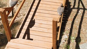 Un puente de madera con barandales, un barril de madera y un pájaro sobre el puente.