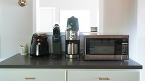 Una encimera de cocina con una cafetera, una licuadora y un microondas.