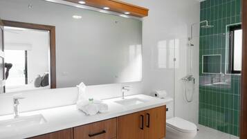Un baño moderno con un espejo grande, dos lavamanos, un inodoro y una ducha.
