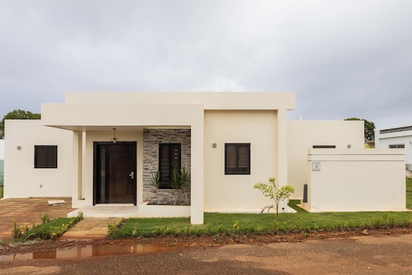 Uma casa moderna de dois andares com fachada de pedra, uma porta principal e duas janelas.
