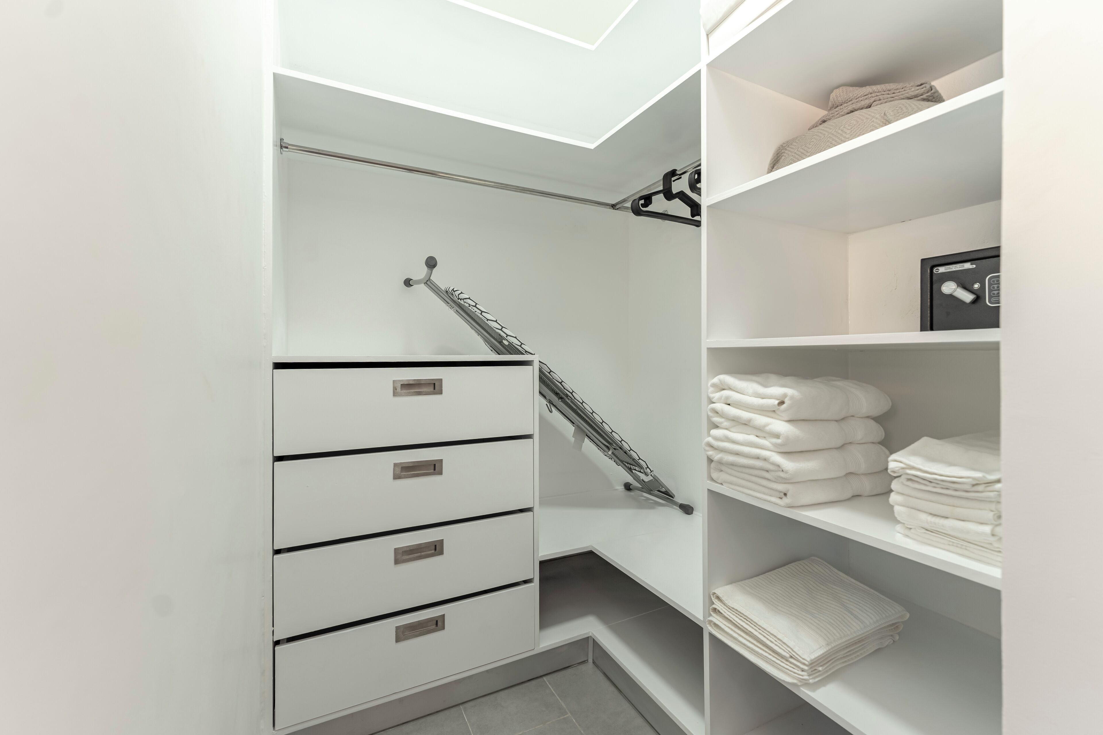 Een moderne badkamer met een inloopdouche, een handdoekrek en netjes opgestapelde handdoeken op planken.