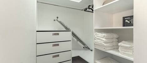 Een moderne badkamer met een inloopdouche, een handdoekrek en netjes opgestapelde handdoeken op planken.