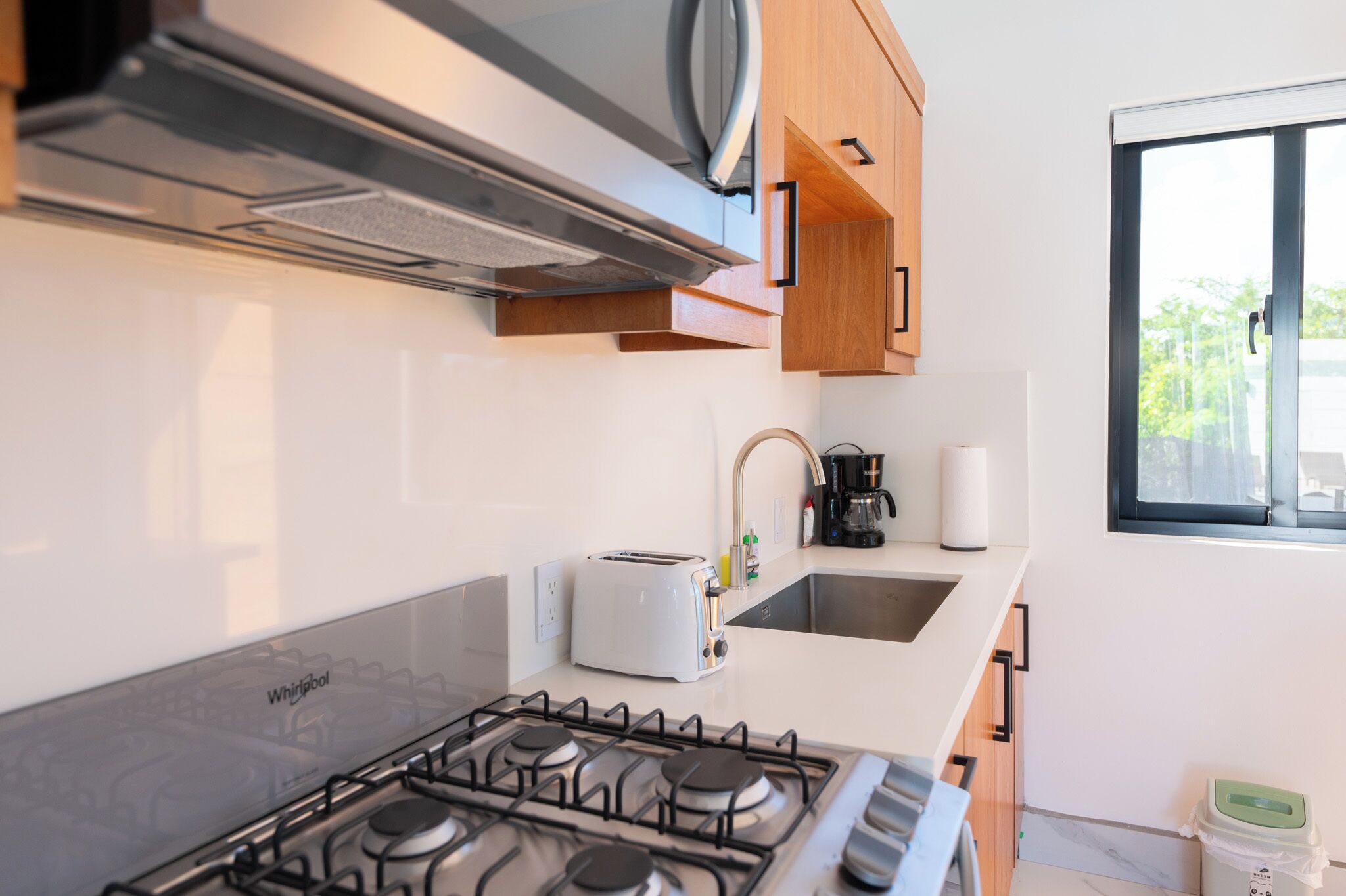A modern kitchen with a gas stove, a toaster, and wooden cabinets.