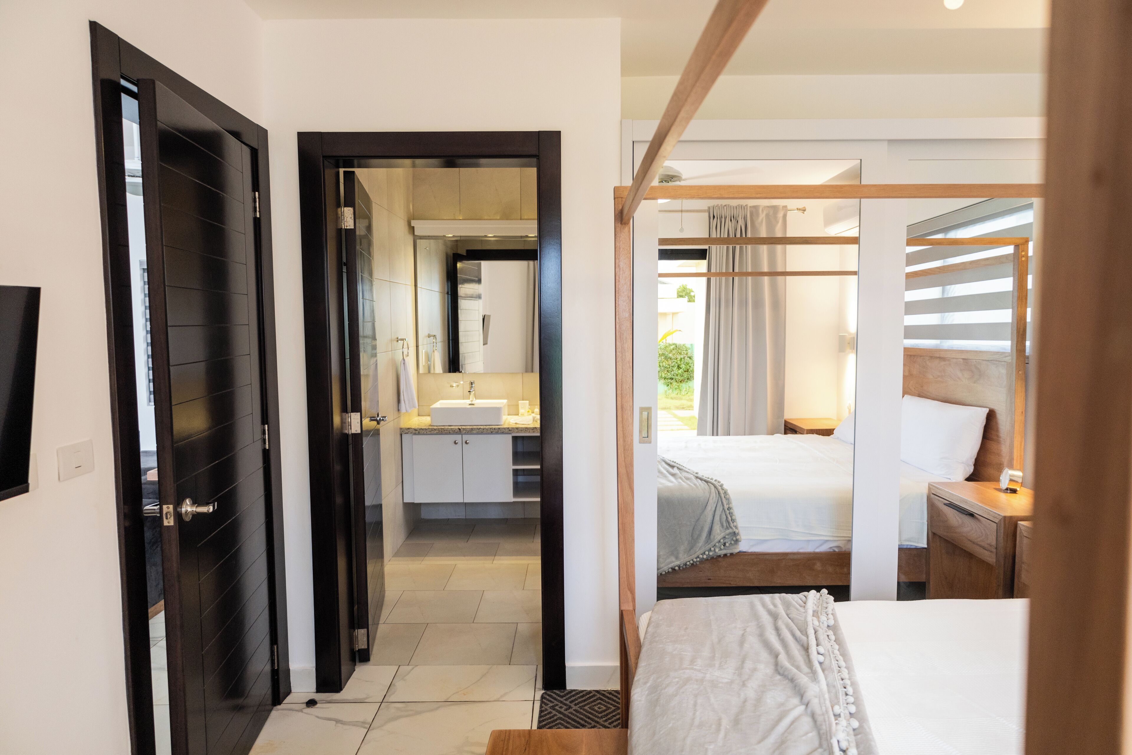 Quarto de hotel com cama, mesa de cabeceira e vista para o banheiro.