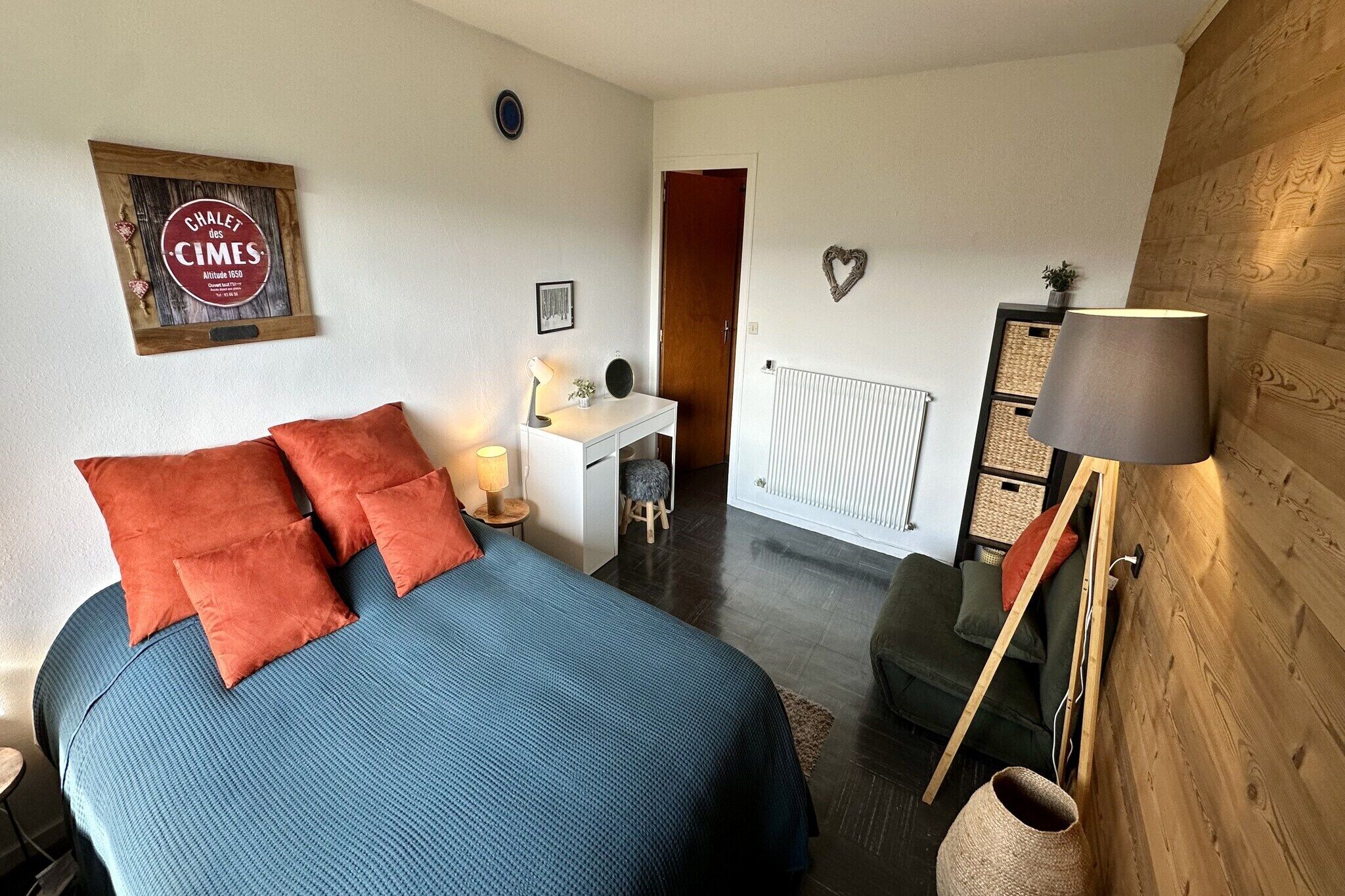 Une chambre à coucher avec un lit, un bureau, une chaise, un radiateur et un mur en bois.
