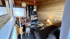 Un acogedor interior de cabaña de madera con una mesa de comedor de madera, un sofá negro y un televisor.