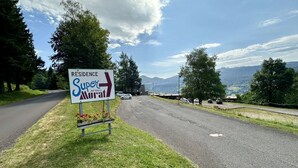 Señal de carretera para 'Residence Super Murat' con una flecha direccional, rodeada de follaje y un cielo despejado.