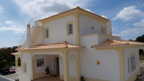 A two-story house with a tiled roof, a balcony, and potted plants. - Villa Mariamar with Private Pool, Wi-Fi, and Air Conditioning (Vale da Azinheira)