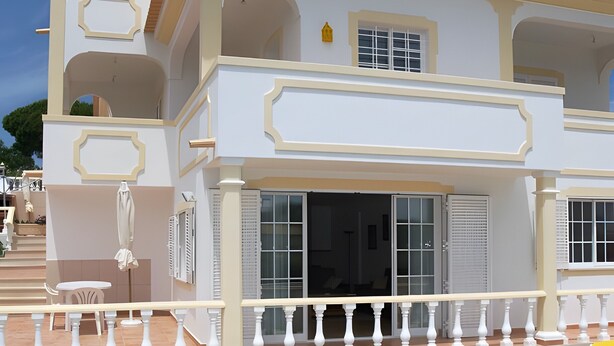 A two-story building with a swimming pool, yellow lounge chairs, and a white balcony railing. - Villa Mariamar with Private Pool, Wi-Fi, and Air Conditioning (Vale da Azinheira)