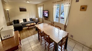 A living room with a sofa, TV, dining table, and chairs. - Sancy refuge by the snowy peak (Mont-Dore)