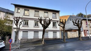 A multi-story building with a flat facade, balconies, and a parking area. - Sancy refuge by the snowy peak (Mont-Dore)