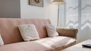 Een woonkamer met een bank, kussens, een lamp en een afstandsbediening op een tafel.