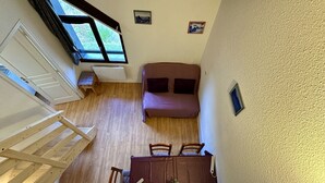 Ein kleines Zimmer mit Bett, Tisch und Fenster.