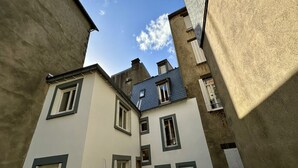 Eine schmale Straße zwischen Gebäuden mit zahlreichen Fenstern und blauem Himmel.