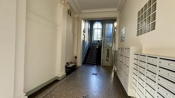 Ein Korridor mit Marmorboden, einer Treppe und einer Reihe von Briefkästen an der rechten Seite.