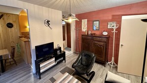 Un soggiorno con televisione, una poltrona in pelle, un mobiletto in legno e una parete rossa.