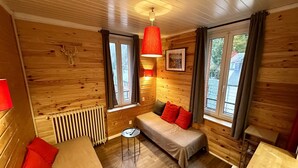 Una stanza accogliente in stile chalet, con un letto, un divano, un tavolino e una lampada a sospensione rossa.