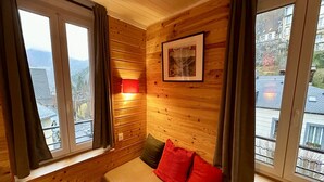 Una stanza con pannelli di legno, un letto, un quadro appeso al muro e una finestra con tende.