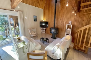 A cozy living room with a fireplace, comfortable seating, and a television. - Luminous escape by the peak path (Mont-Dore)