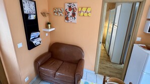 Een kamer met een bruine leren bank, een wandklok en drie ingelijste kunstwerken.