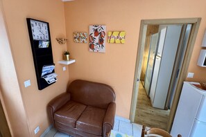 Ein Zimmer mit einem braunen Ledersofa, einer Wanduhr und drei gerahmten Kunstwerken.