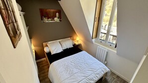 Ein Schlafzimmer mit Bett, Nachttischlampen, Heizkörper und Fenster mit Ausblick nach draußen.