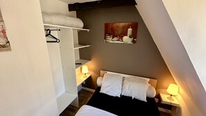 Ein Schlafzimmer mit einem Bett, Nachttischlampen, einem Kleiderschrank und einem Bild an der Wand.