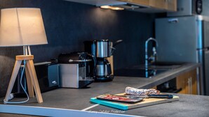 A modern kitchen with a coffee maker, a lamp, and a cutting board with a packaged food item. - Estate with Panoramic Sancy Views (Mont-Dore)