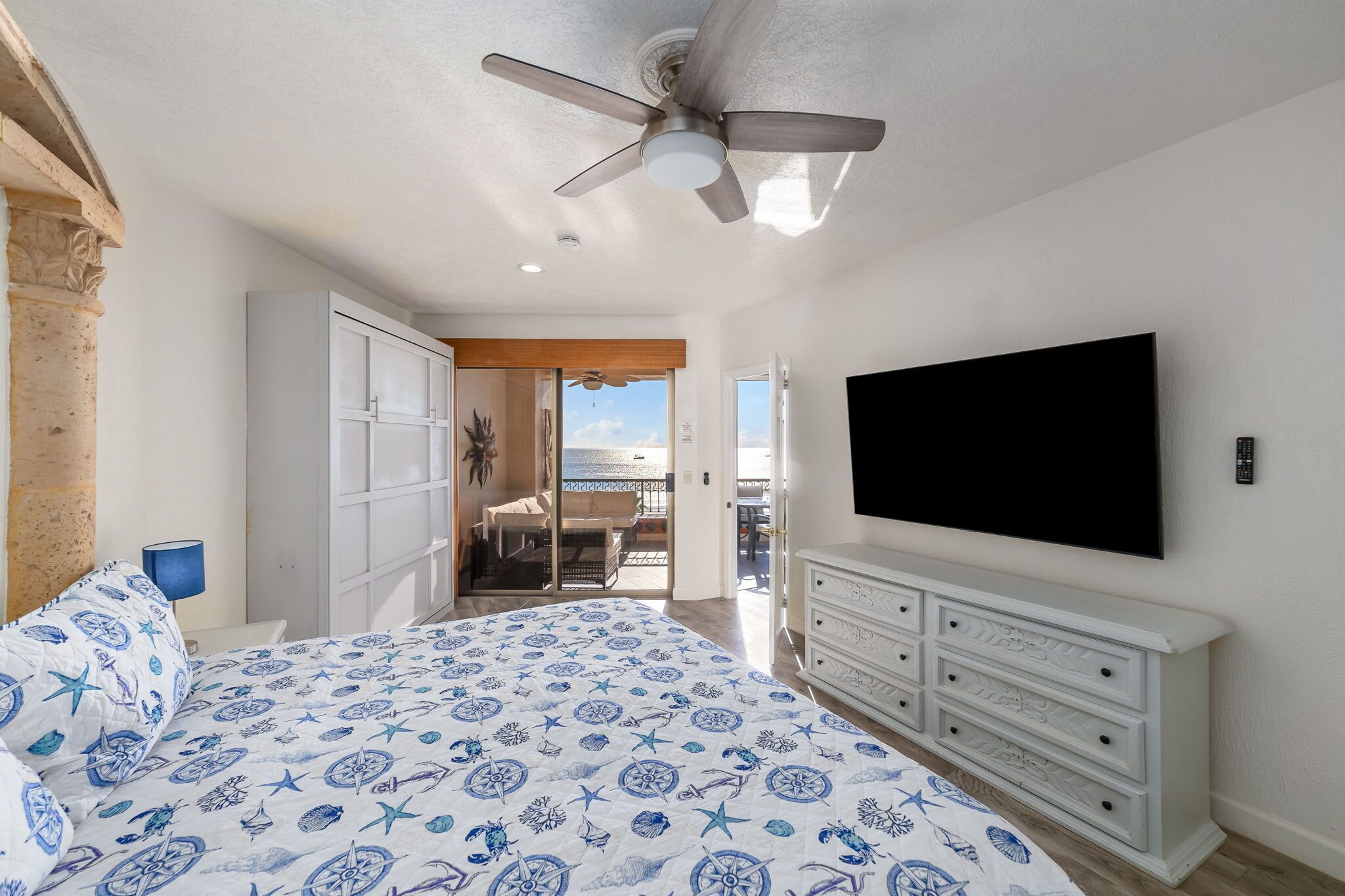 Un dormitorio con cama, ventilador de techo, televisor y cómoda.