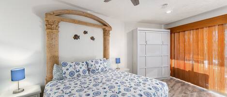 A bedroom with a bed, a ceiling fan, a wardrobe, and a window with curtains.