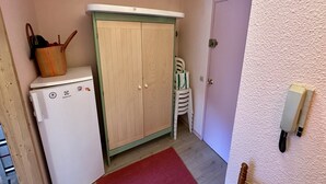 Ein gemütlicher Raum mit einem Holzschrank, einem kleinen Kühlschrank, einem roten Teppich und einem weißen Wandtelefon.