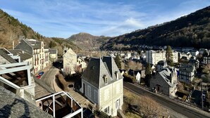 Eine Stadt mit einer Mischung aus moderner und traditioneller Architektur, darunter ein markantes Steinhaus mit steilem Dach und eine moderne Glasstruktur.