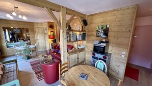 Ein gemütliches Blockhaus-Interieur mit Essbereich, einem roten Sofa und einer Küchenzeile.