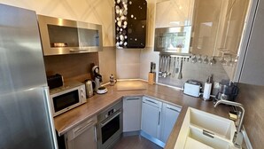 A modern kitchen with stainless steel appliances, a dishwasher, and a sink. - Quiet corner near the mountain road (Mont-Dore)